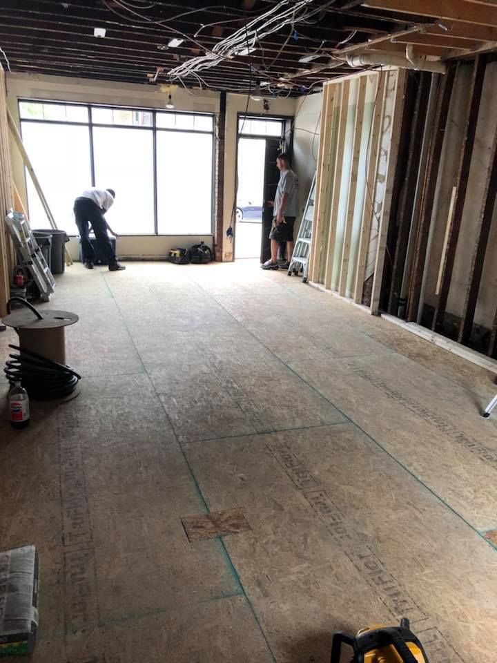A man is standing in the middle of a large room under construction.