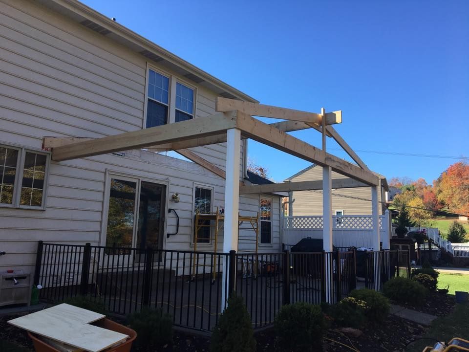 A white house with a fence and a wooden pergola on the backyard.