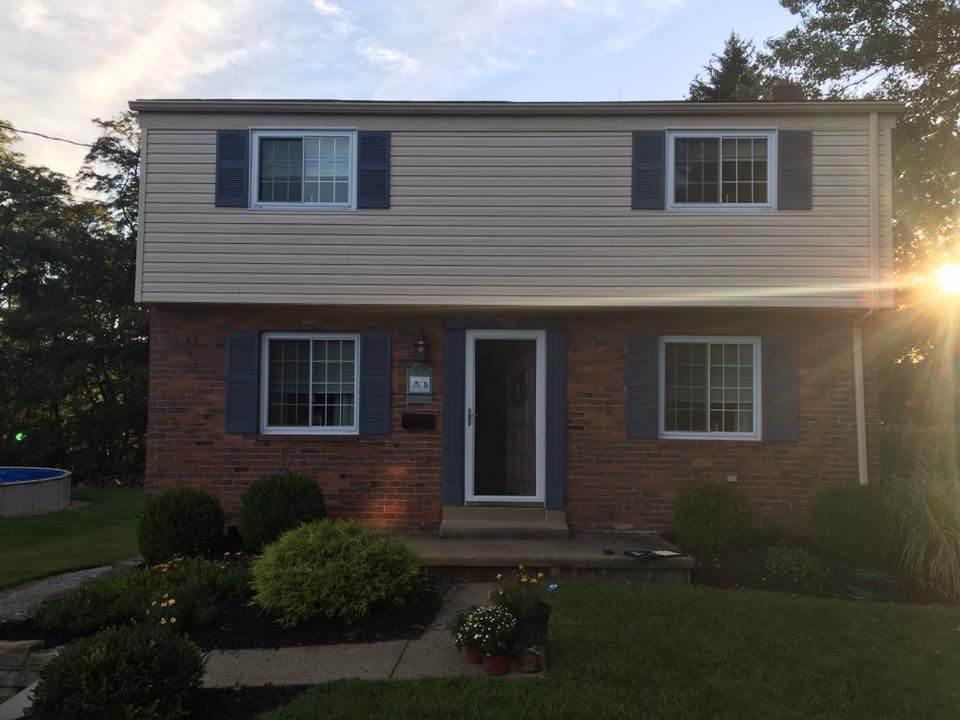A brick house with white siding and blue shutters