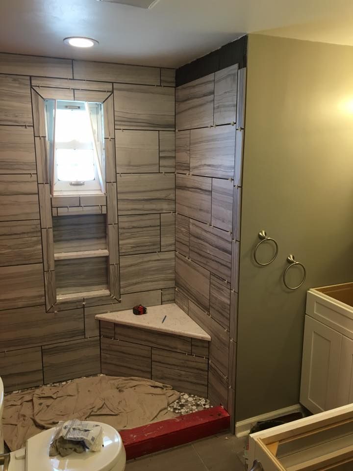 A bathroom is being remodeled with a walk in shower and a window.