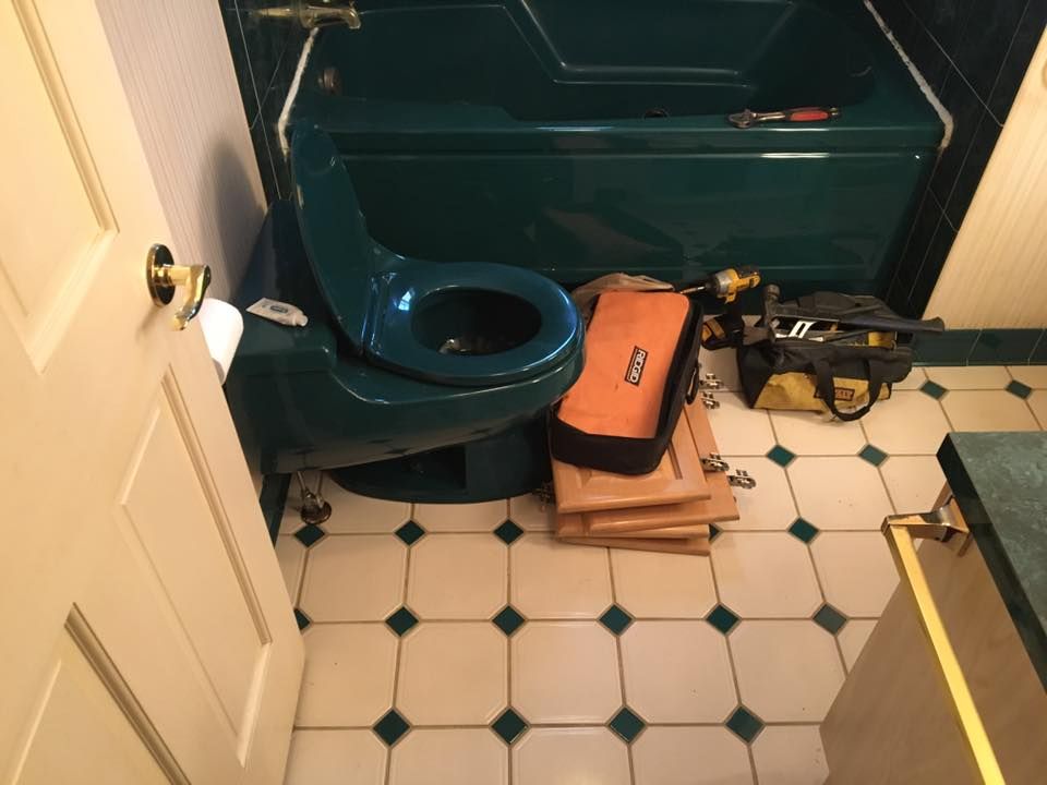 A bathroom with a toilet a bathtub and a tool bag