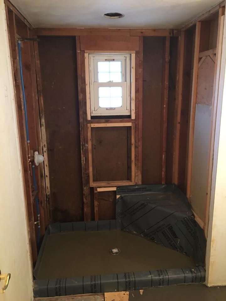A bathroom under construction with a window and a shower stall.