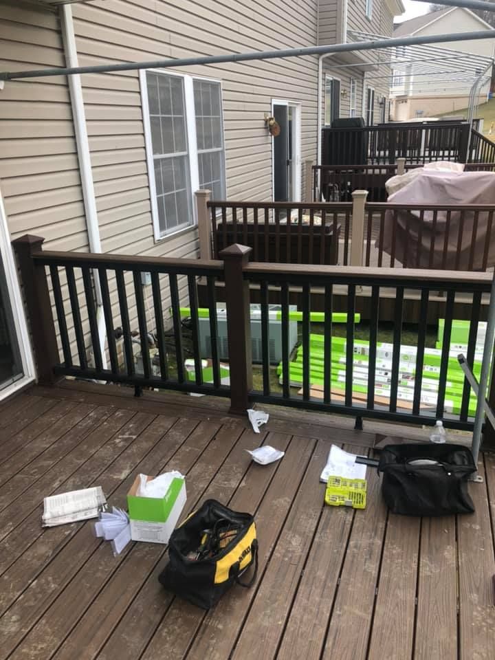 A wooden deck with a black railing and a bag of tools on it.