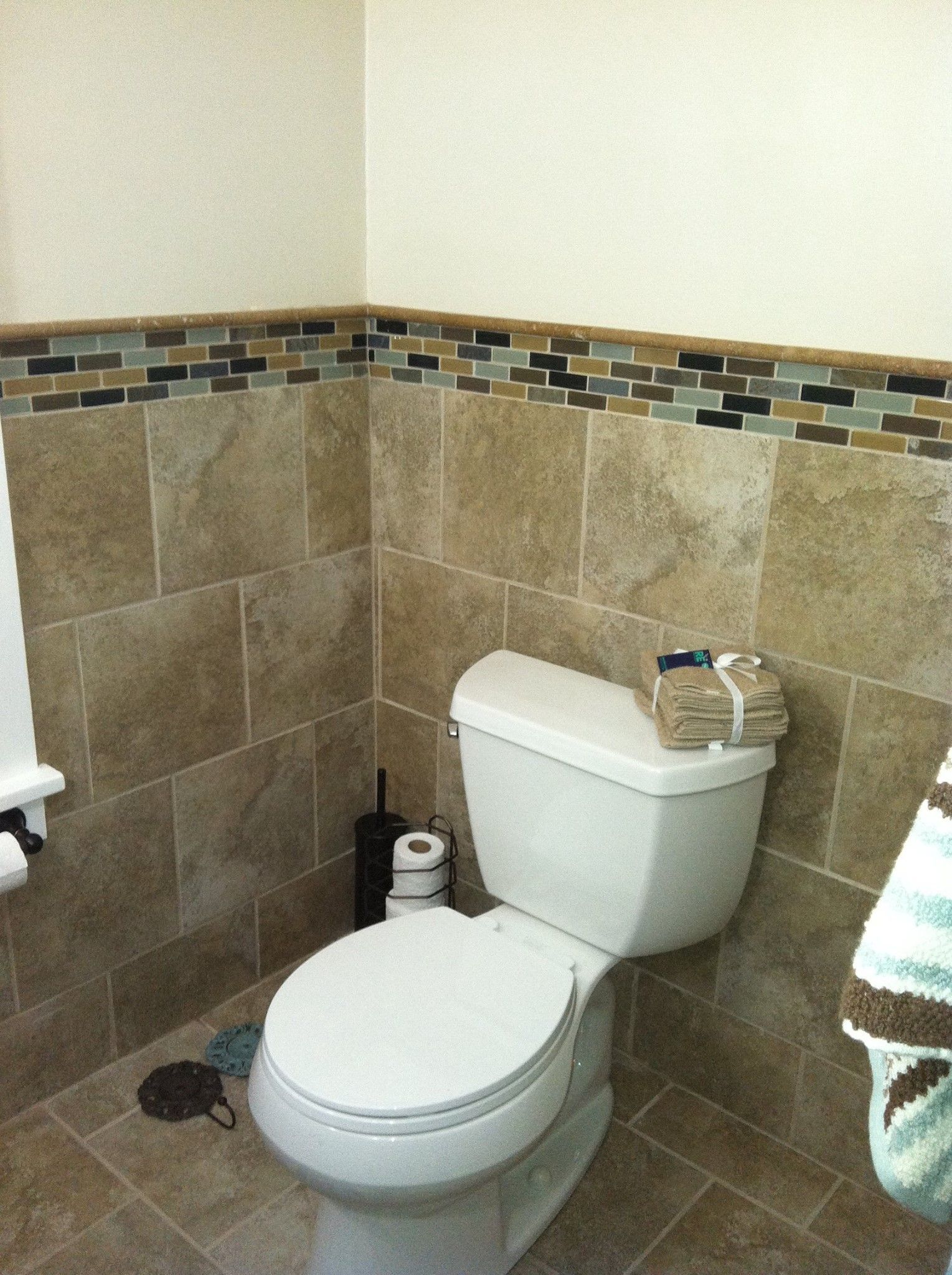 A toilet in a bathroom with a basket on top of it.