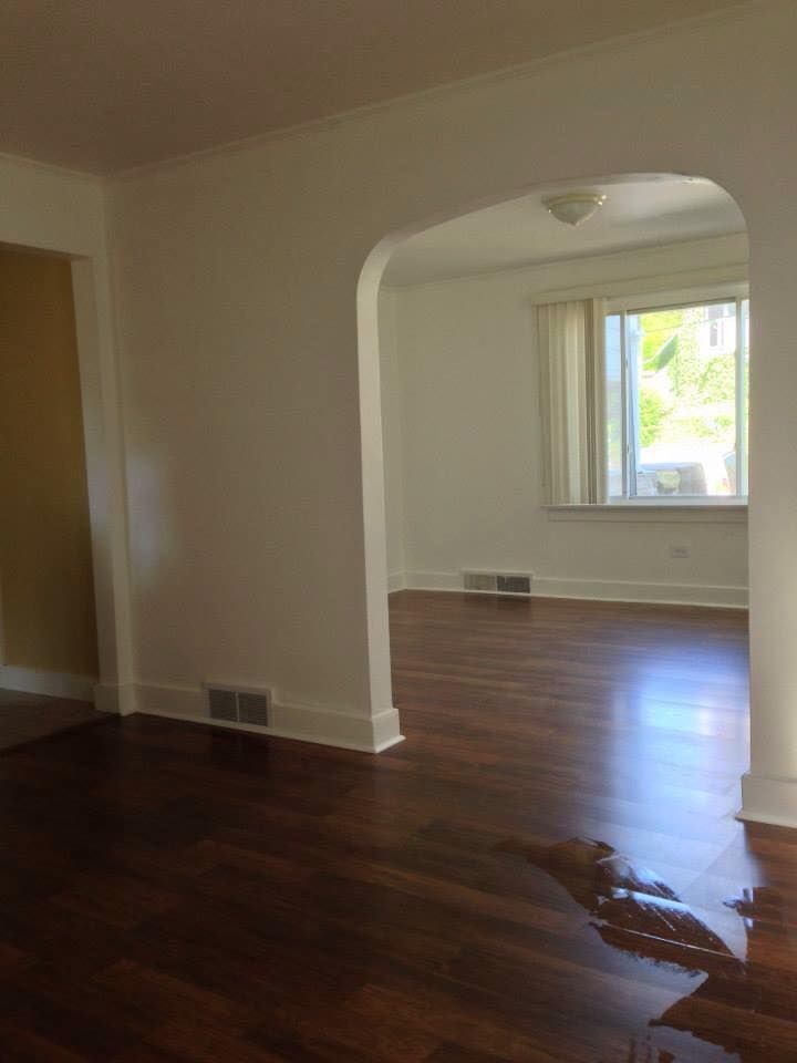 An empty living room with hardwood floors and white walls.