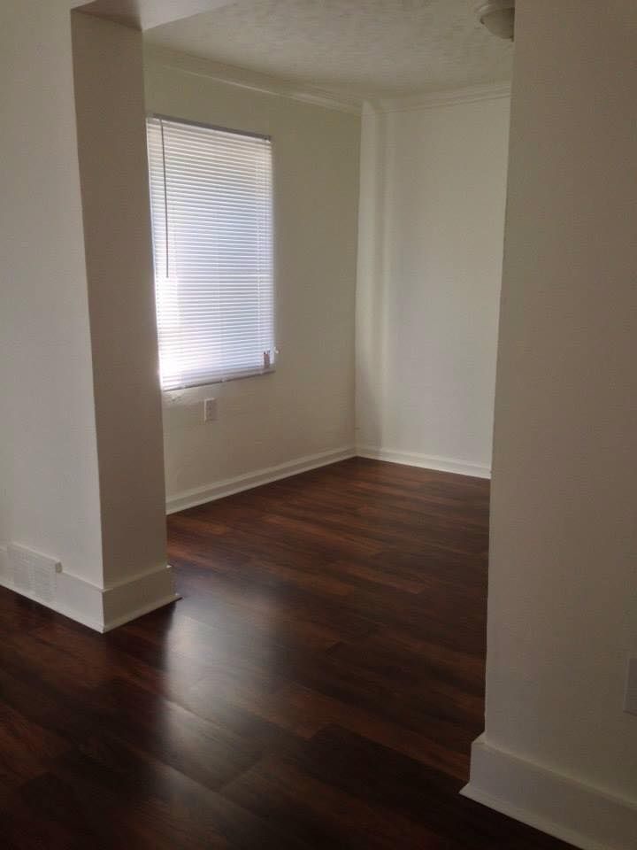 An empty room with hardwood floors and a window.