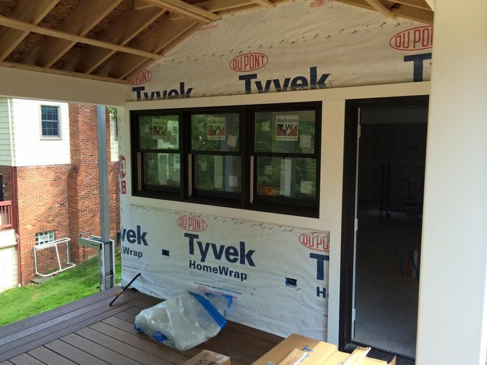A window is being installed on a porch with tyvek insulation