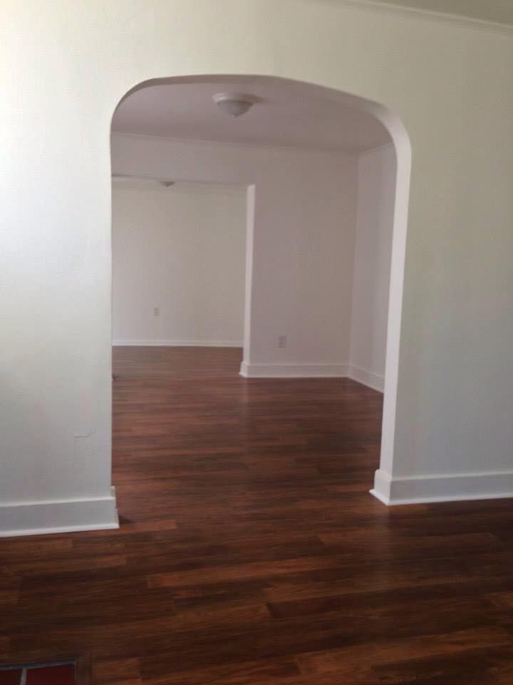 An empty living room with hardwood floors and white walls.