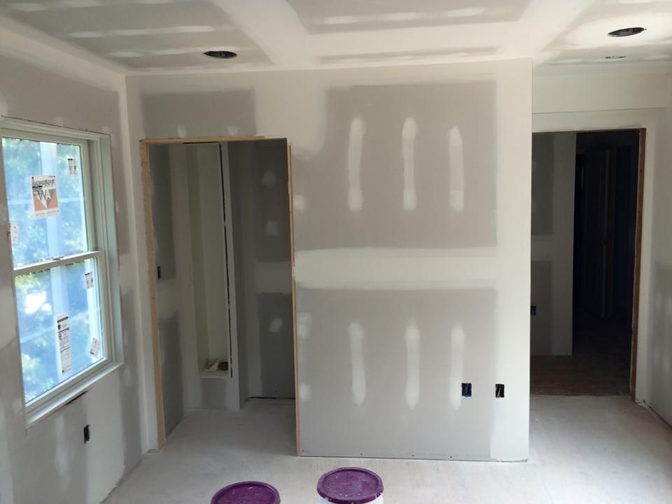 A room with drywall and two buckets of paint on the floor.