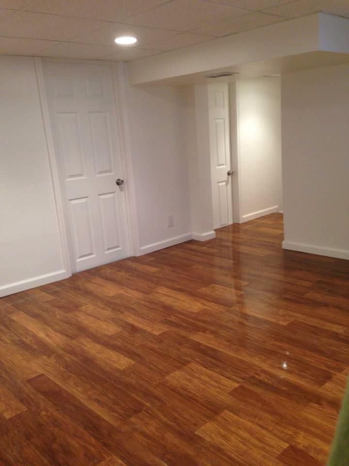 An empty basement with hardwood floors and white walls.