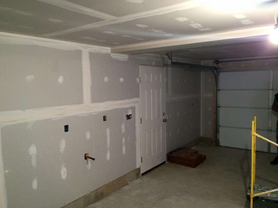 A garage is being remodeled with drywall and a garage door.