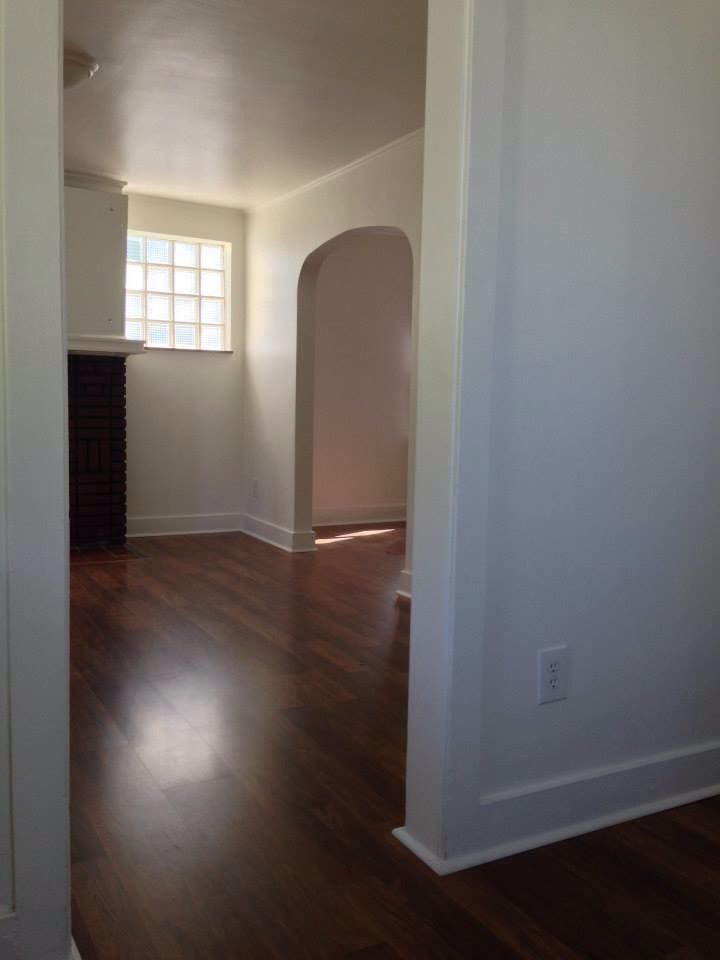 An empty living room with hardwood floors and white walls.
