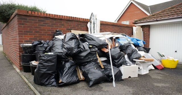 A pile of garbage bags in front of a garage