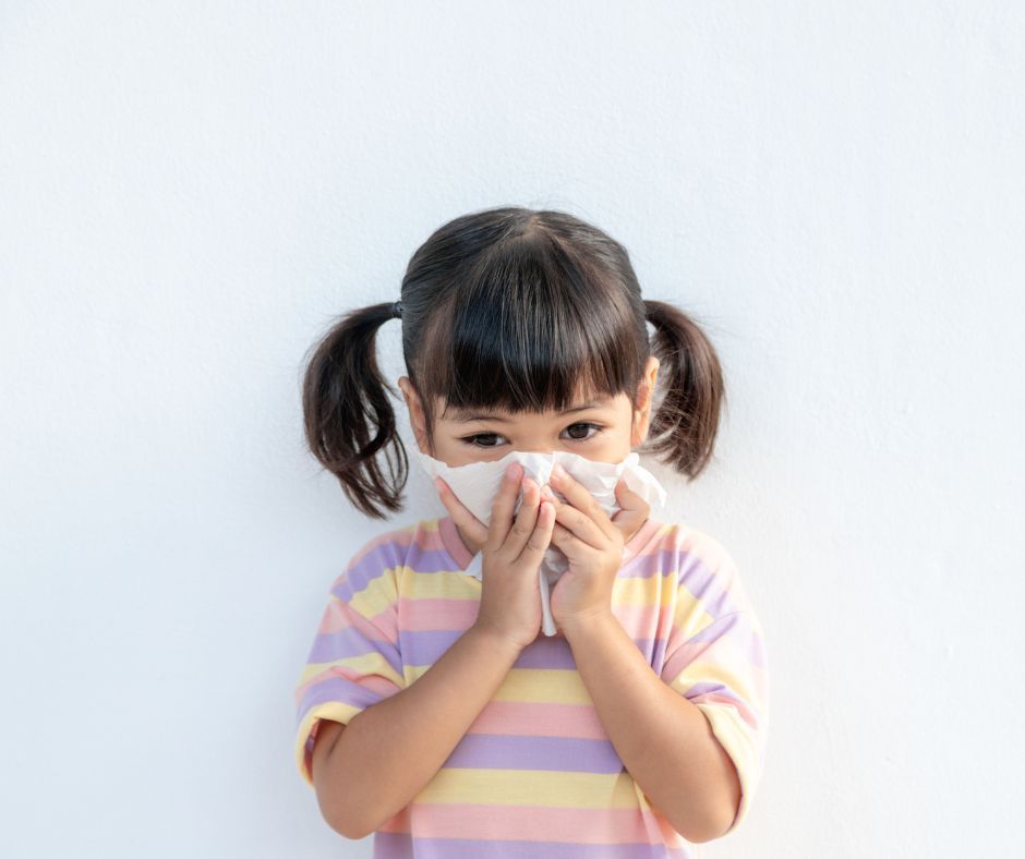 A little girl is blowing her nose with a napkin