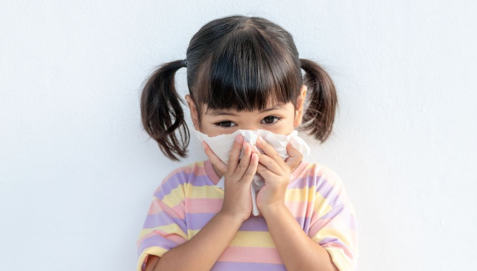 A little girl is blowing her nose with a napkin