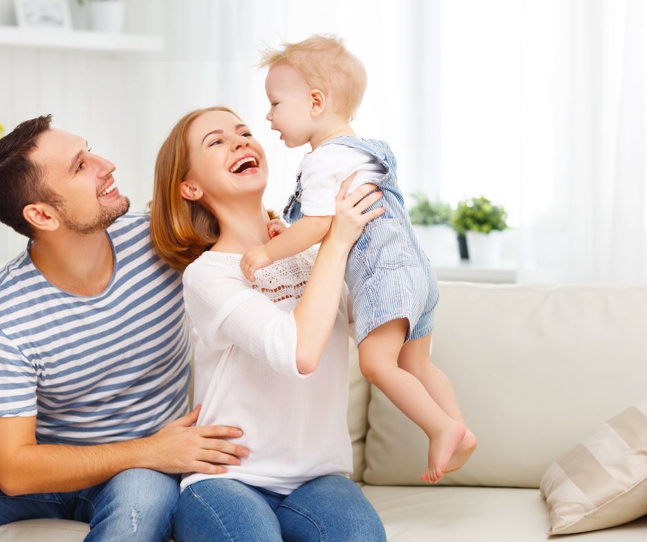 A family is sitting on a couch holding a baby