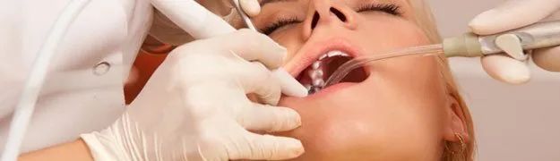 A woman is getting her teeth examined by a dentist.