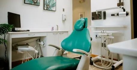 A dental office with a green dental chair and a desk.