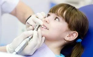 A little girl is getting her teeth examined by a dentist.