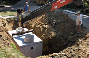 Crane putting septic tank in ground