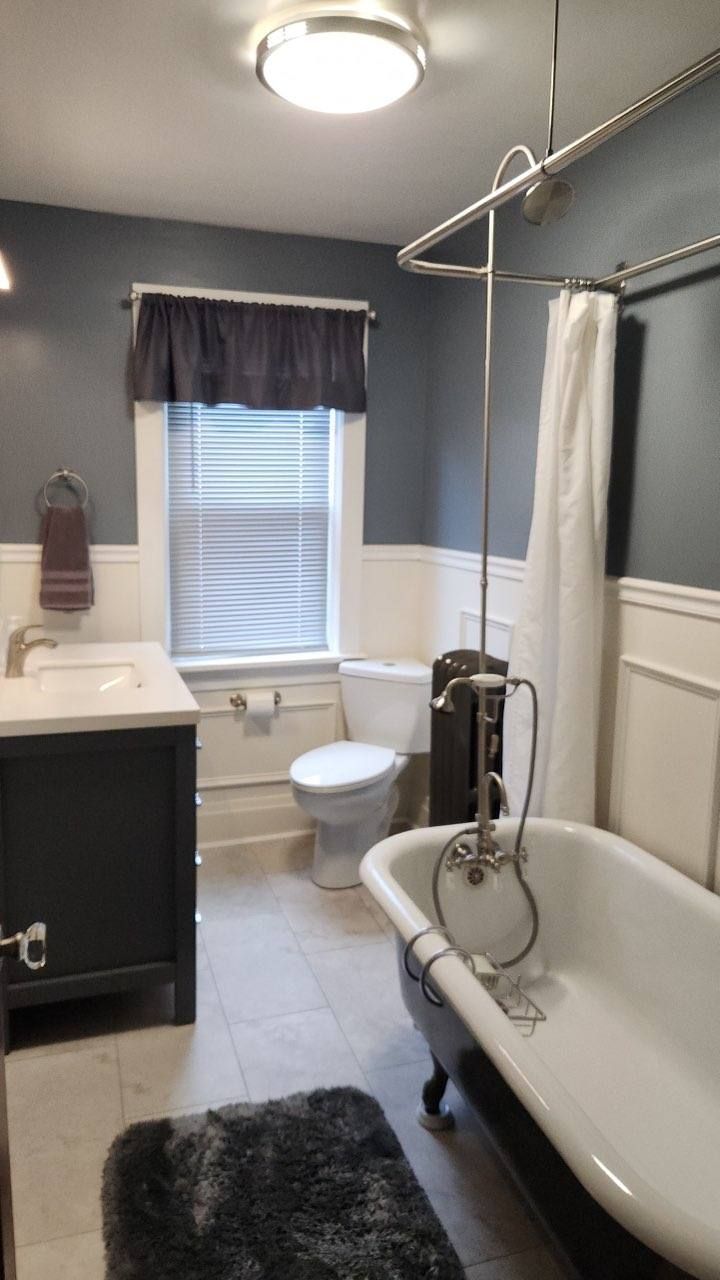 A bathroom with a tub, toilet, sink, and window.