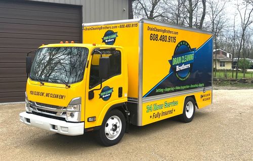 Two men are standing in front of a yellow and blue truck.