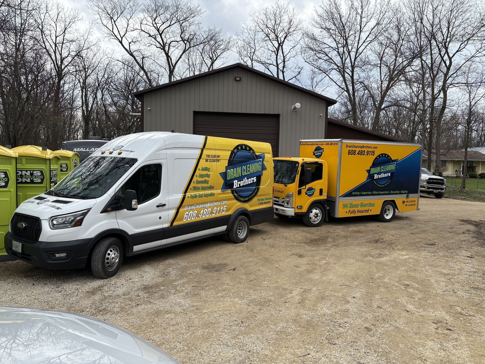 Three vans are parked in a gravel lot in front of a building.