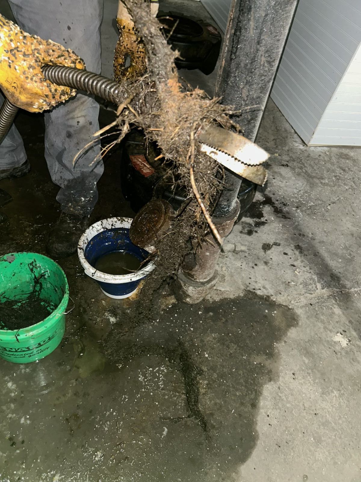 A person is cleaning a drain with a hose.