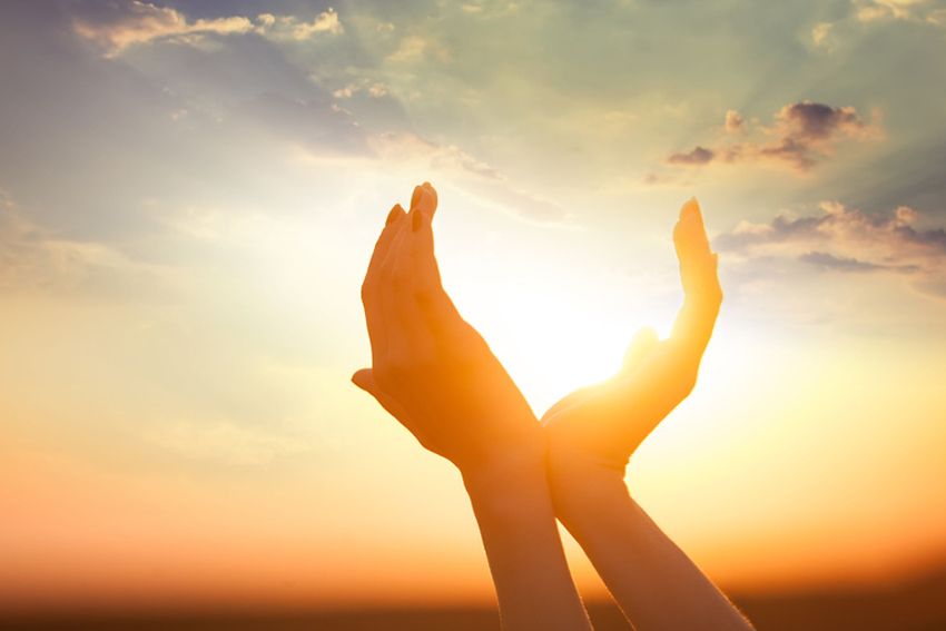 Hands holding the sun at dawn