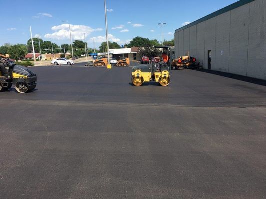 A row of tractors are parked in a parking lot in front of a building.