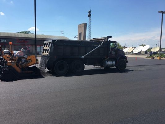A dump truck is parked in a parking lot next to a bulldozer.