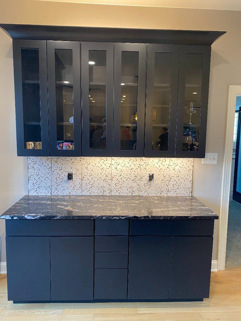 A kitchen with black cabinets and a granite counter top.