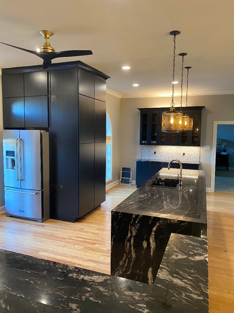 A kitchen with black cabinets and a ceiling fan