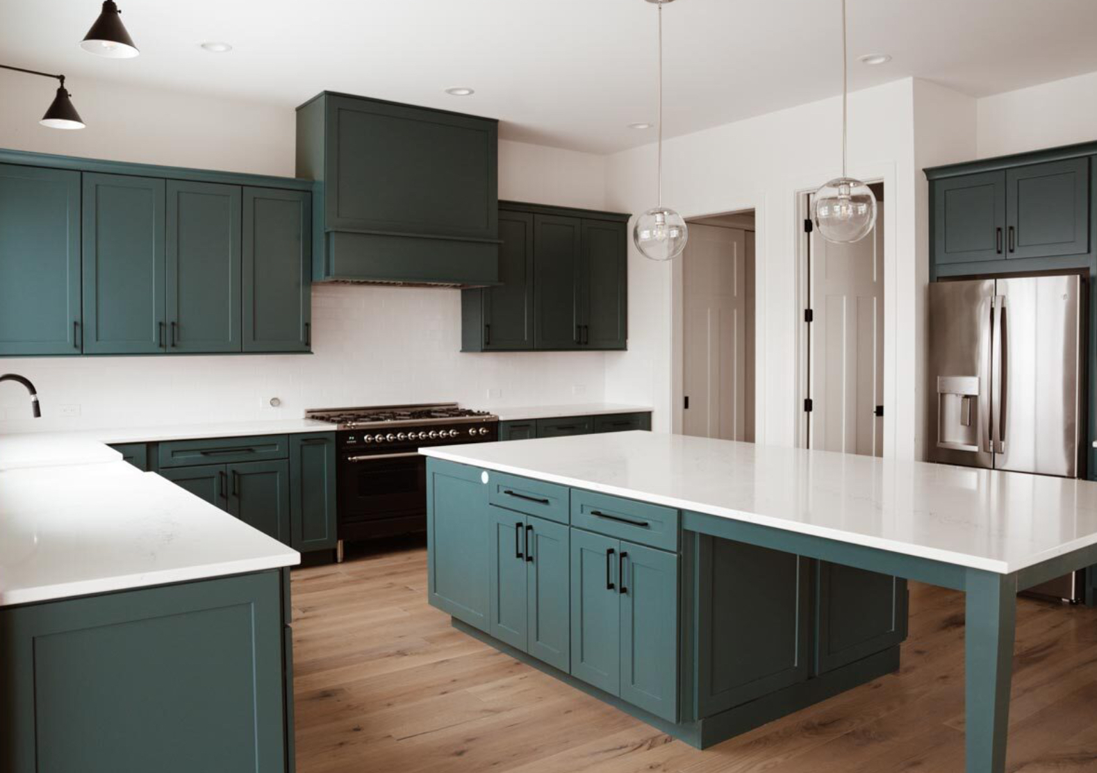 A kitchen with green cabinets , white counter tops , and a large island.