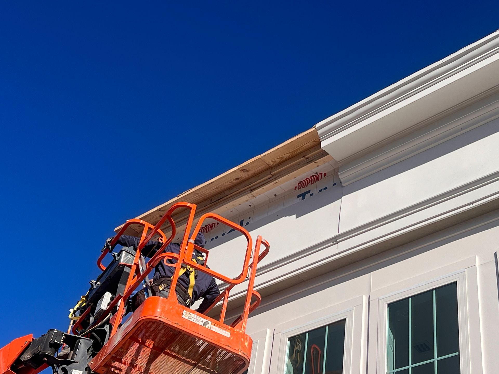 A man is working on the side of a building on a lift.