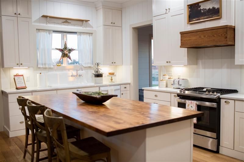 A kitchen with white cabinets and a large wooden island.