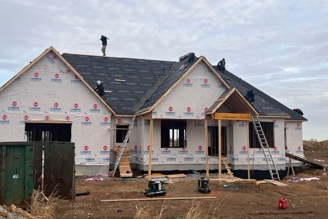 A house is being built in a field and the roof is being installed.