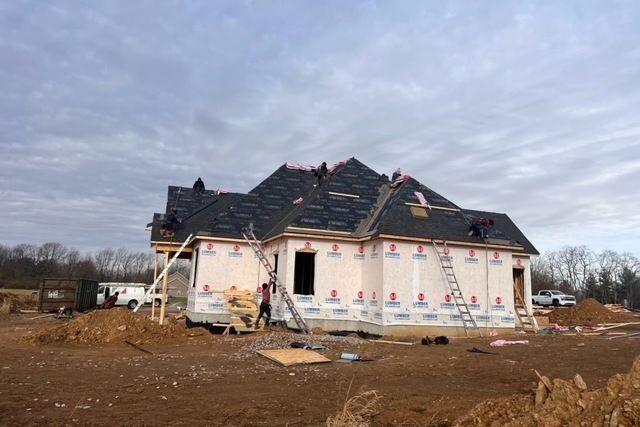 A house is being built in a field and the roof is being installed.