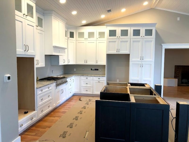 A kitchen with white cabinets and a black island in the middle