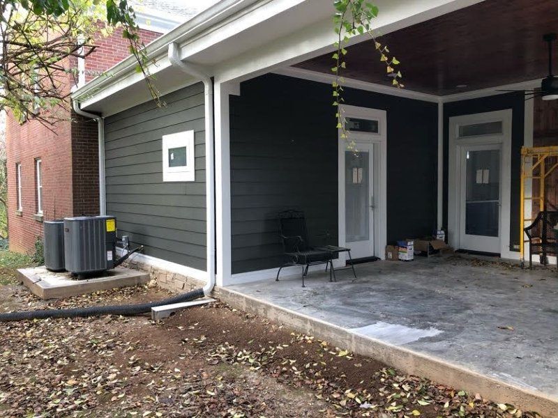 A house with a covered porch and two air conditioners on the side of it.