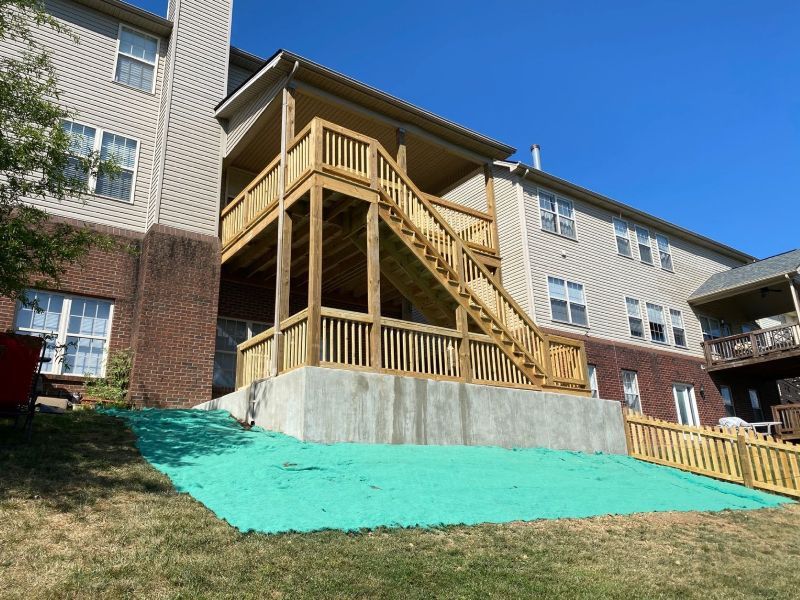 A large house with a wooden deck and stairs in front of it.