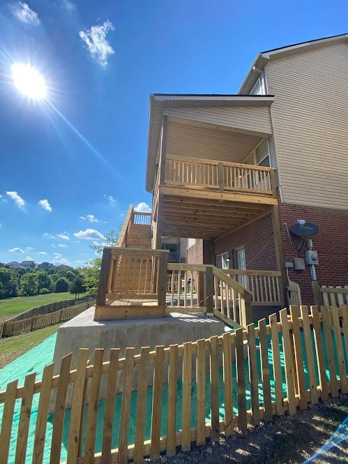 A house with a wooden deck and a wooden fence in front of it.