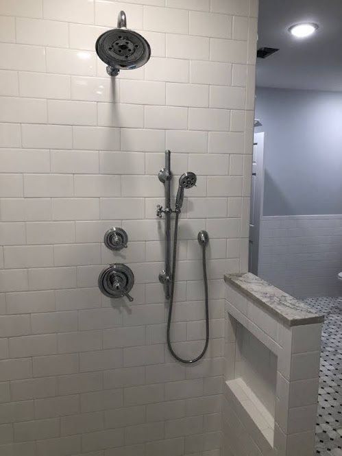 A shower with white tiles and a shower head.