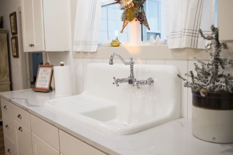 A kitchen sink with a potted plant on the counter.