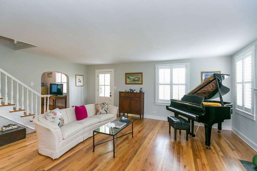 A living room with a piano, couch, coffee table and stairs