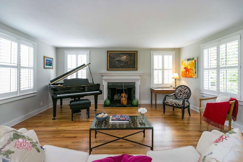 A living room with a piano, fireplace, couch and chairs