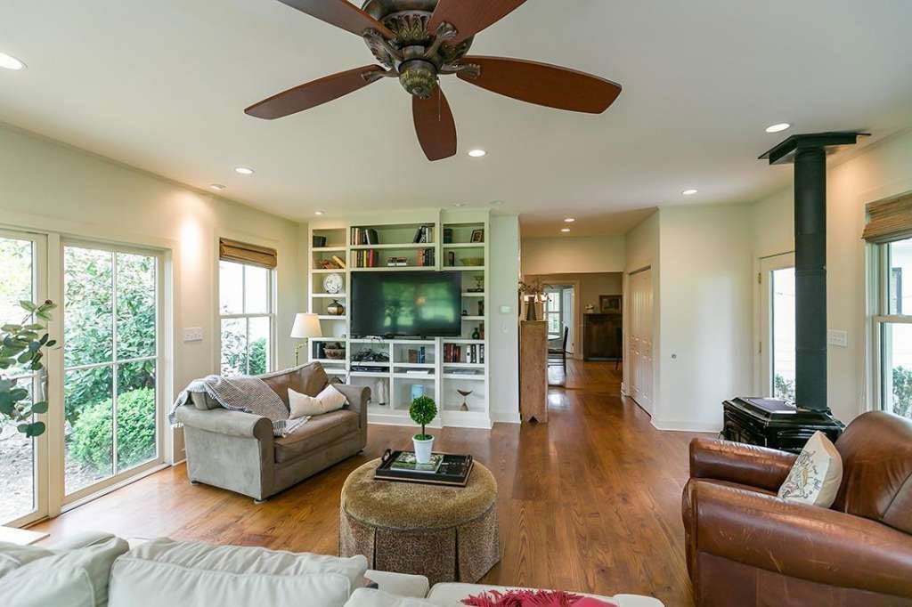 A living room with a ceiling fan and a flat screen tv