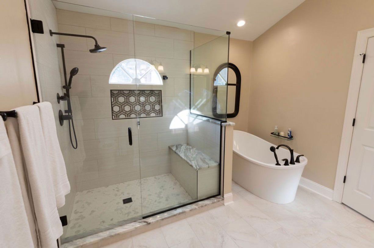 A bathroom with a walk in shower, tub and mirror