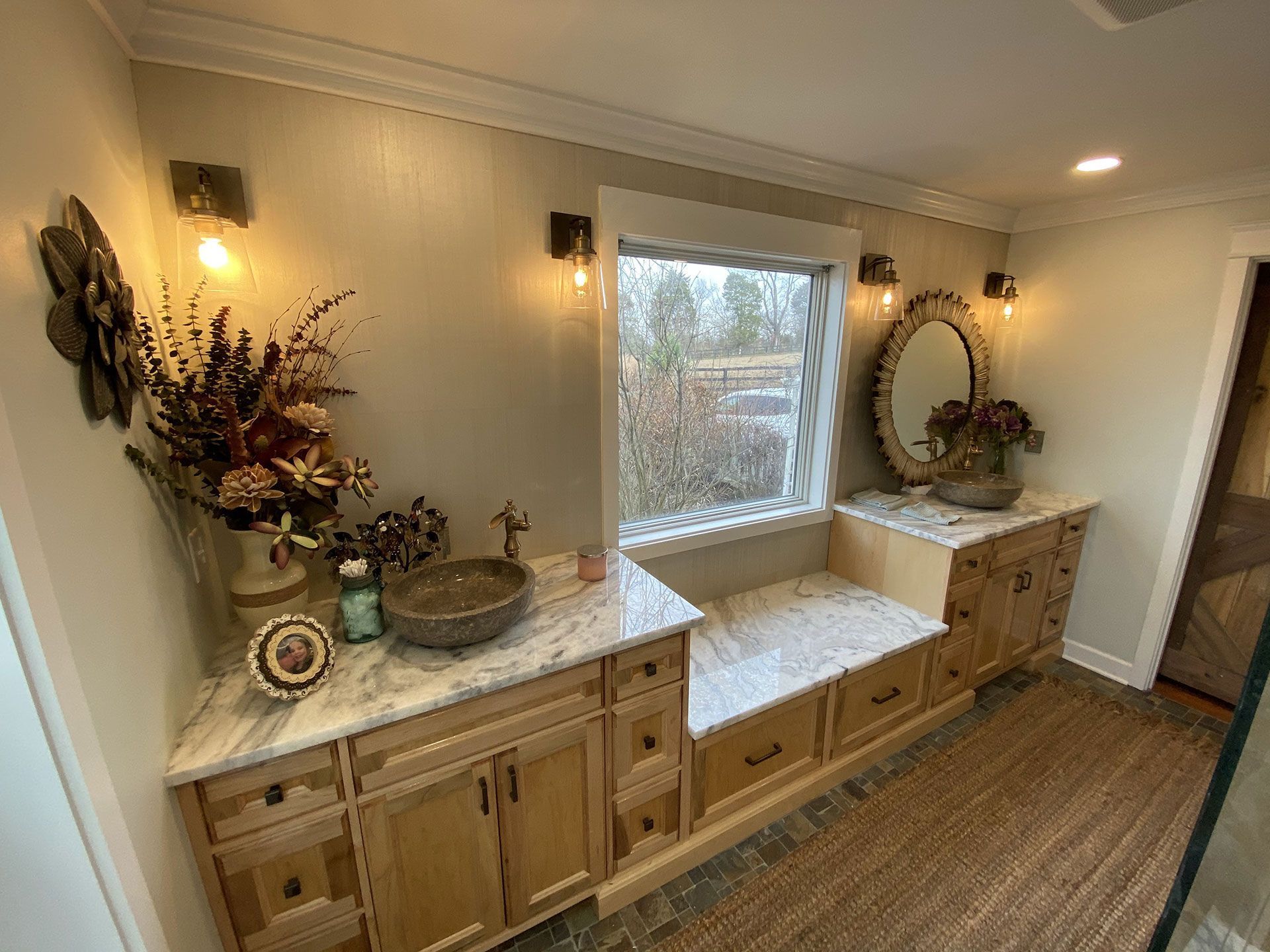 A bathroom with a sink , mirror and window.