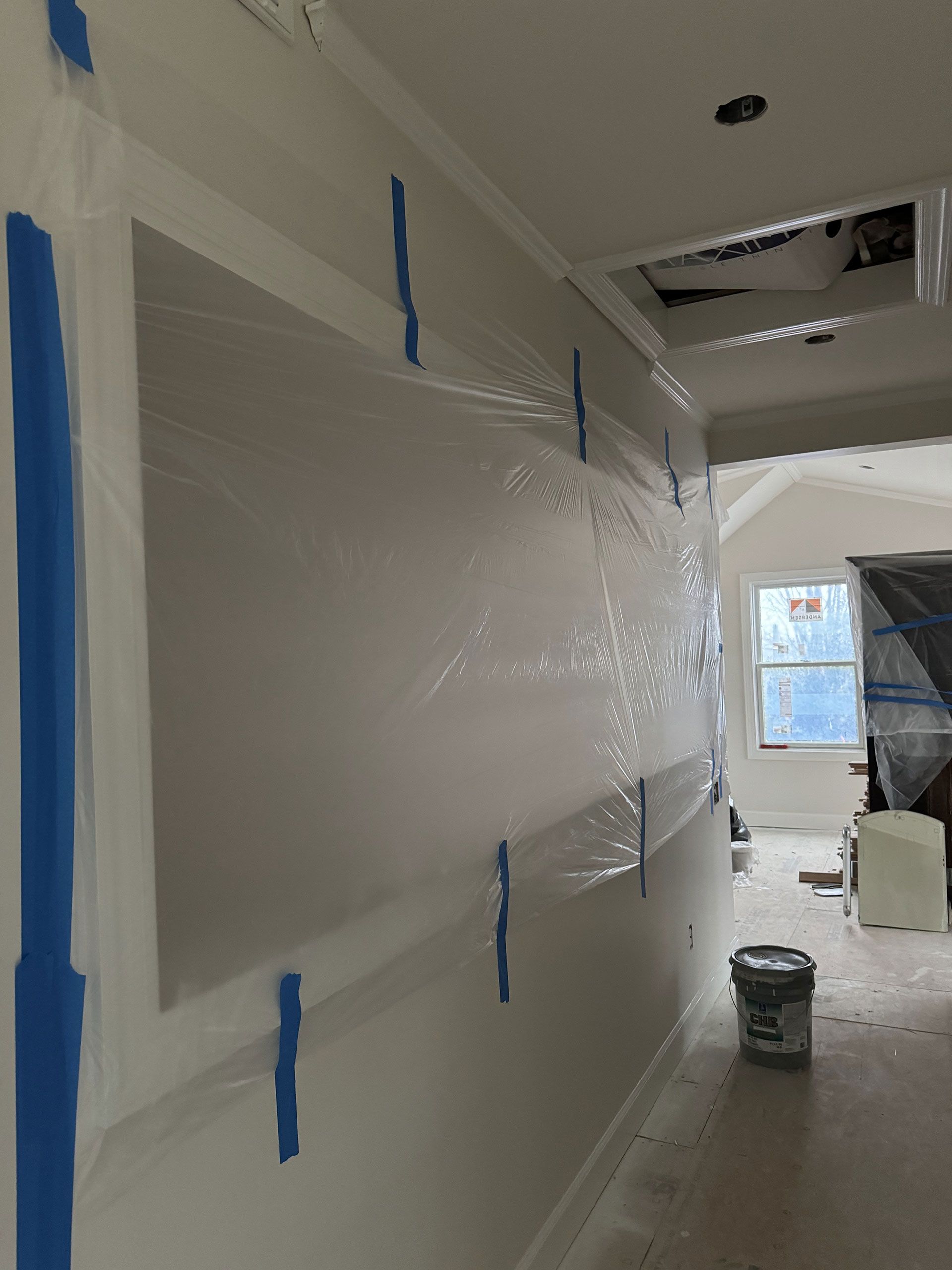 A white wall with blue tape on it is being painted.